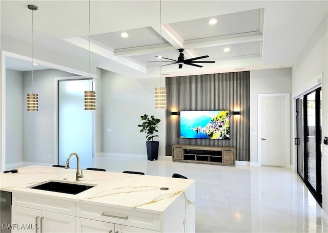 kitchen with open floor plan, white cabinets, a sink, light stone countertops, and coffered ceiling