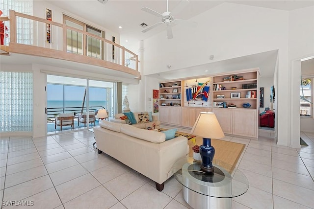 living room with a high ceiling, light tile patterned floors, a ceiling fan, and visible vents