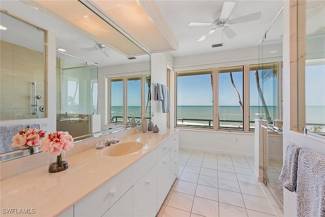 full bathroom featuring a ceiling fan, tiled shower, tile patterned flooring, baseboards, and vanity