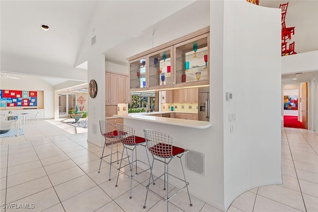 bar featuring light tile patterned floors, visible vents, vaulted ceiling, and stainless steel fridge with ice dispenser