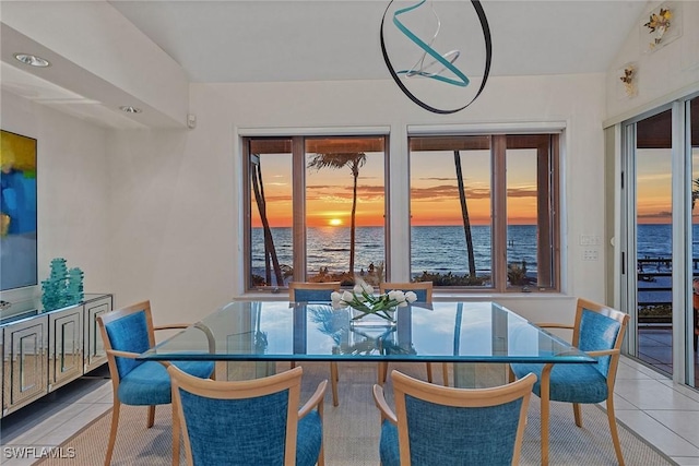 dining area with tile patterned flooring, a healthy amount of sunlight, and a water view