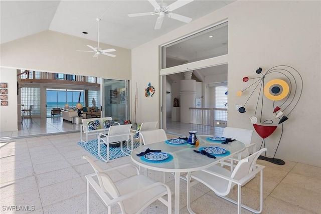 dining space featuring a ceiling fan, speckled floor, and high vaulted ceiling