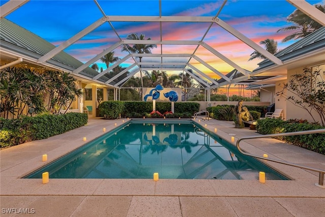 pool at dusk with glass enclosure, a patio area, and a fenced in pool