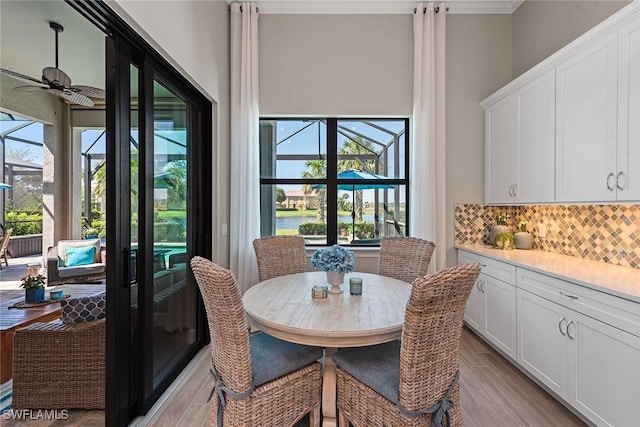 dining area with plenty of natural light, a water view, a ceiling fan, and light wood-style floors