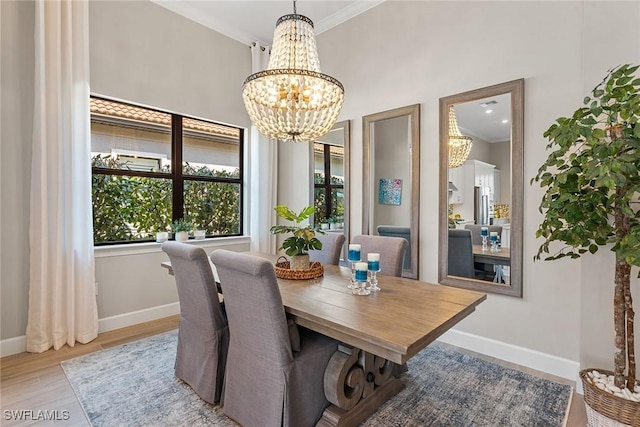 dining area featuring ornamental molding, a notable chandelier, baseboards, and wood finished floors