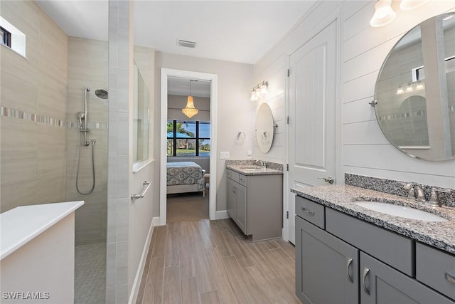 ensuite bathroom with visible vents, a walk in shower, and a sink