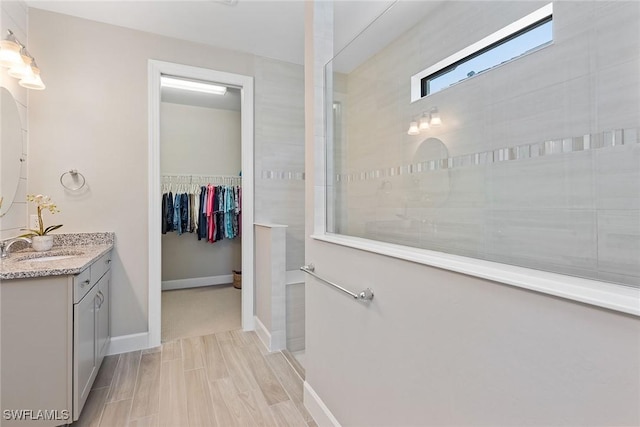 full bathroom with a walk in closet, vanity, and a walk in shower