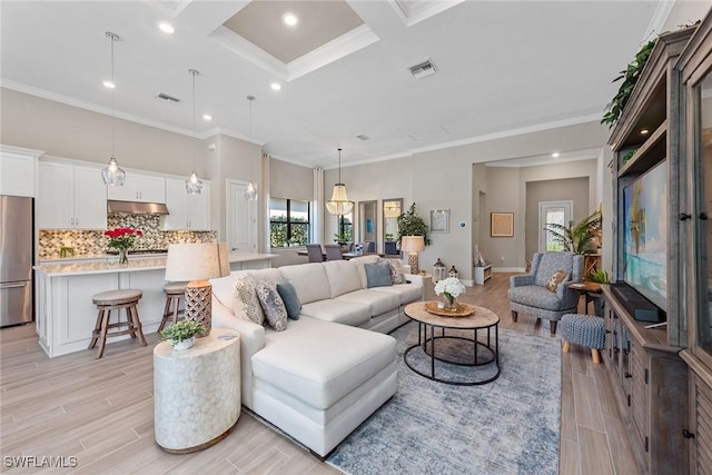 living area featuring visible vents, crown molding, light wood-style flooring, and a high ceiling