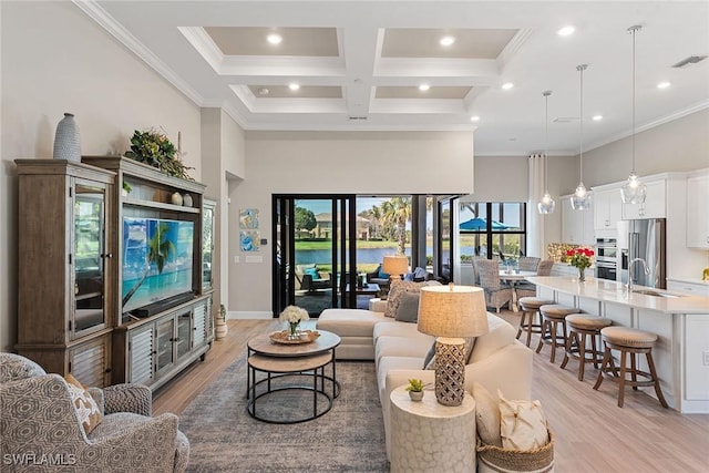 living area with ornamental molding, coffered ceiling, light wood finished floors, and a high ceiling