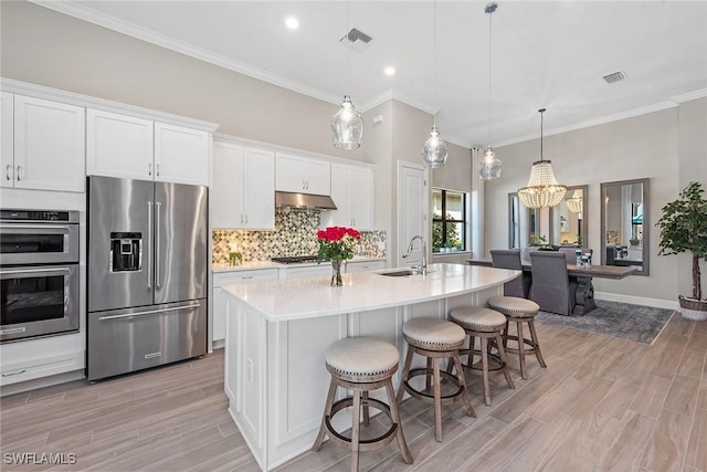 kitchen featuring visible vents, a sink, stainless steel appliances, under cabinet range hood, and backsplash