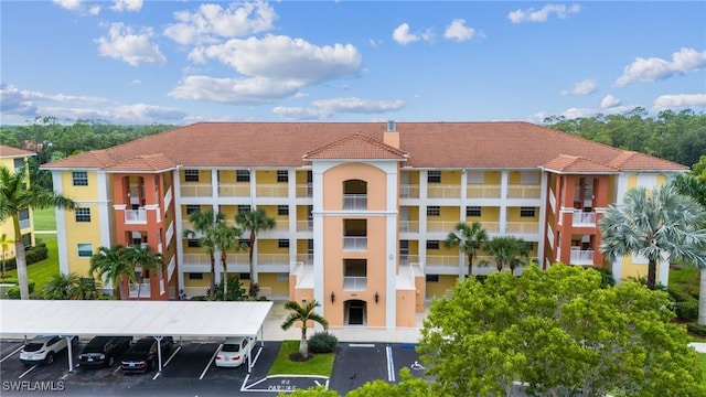 view of building exterior with covered and uncovered parking