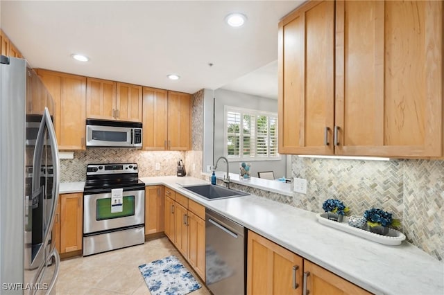 kitchen with light tile patterned floors, a sink, light countertops, appliances with stainless steel finishes, and tasteful backsplash