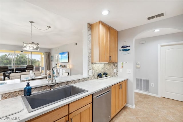 kitchen with decorative backsplash, visible vents, a sink, and stainless steel dishwasher