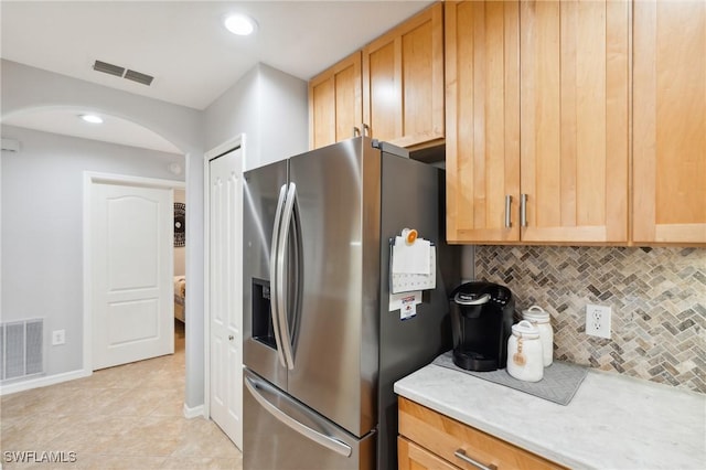 kitchen featuring light countertops, tasteful backsplash, stainless steel refrigerator with ice dispenser, and visible vents