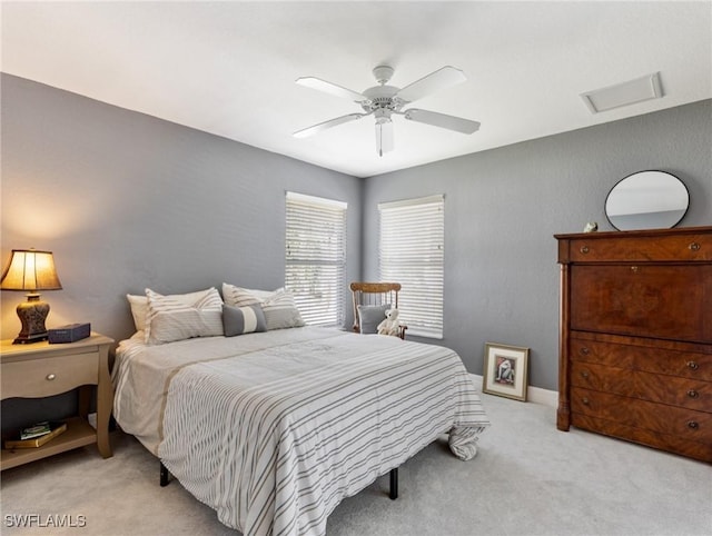 carpeted bedroom with visible vents, attic access, and a ceiling fan