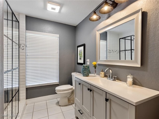 bathroom featuring toilet, a textured wall, tile patterned flooring, and vanity