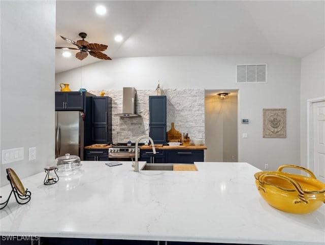 kitchen with stainless steel appliances, visible vents, vaulted ceiling, and wall chimney range hood