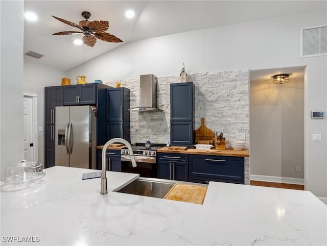 kitchen with visible vents, lofted ceiling, appliances with stainless steel finishes, blue cabinetry, and wall chimney range hood