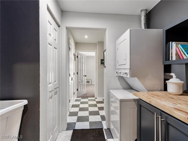 bathroom featuring stacked washing maching and dryer, baseboards, and tile patterned floors