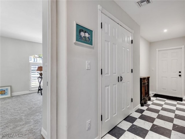 hallway featuring baseboards, visible vents, carpet flooring, and tile patterned floors