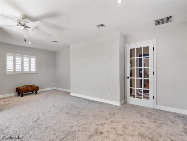 carpeted empty room with a ceiling fan, visible vents, and baseboards