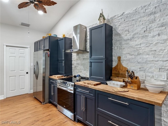 kitchen with visible vents, wall chimney range hood, butcher block counters, and appliances with stainless steel finishes