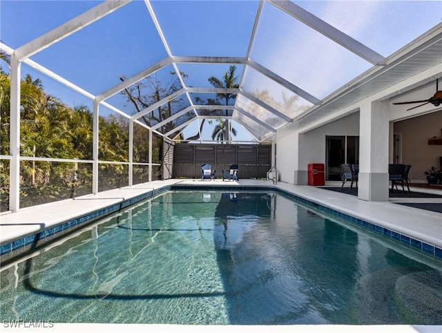 outdoor pool featuring a patio area, glass enclosure, and a ceiling fan