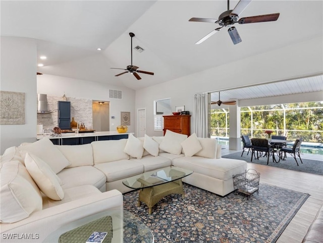 living room with a sunroom, wood finished floors, visible vents, and a ceiling fan