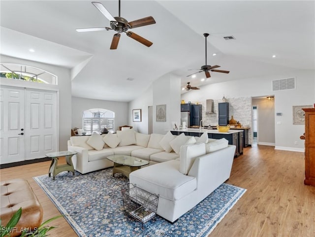 living room featuring lofted ceiling, visible vents, and light wood-style floors