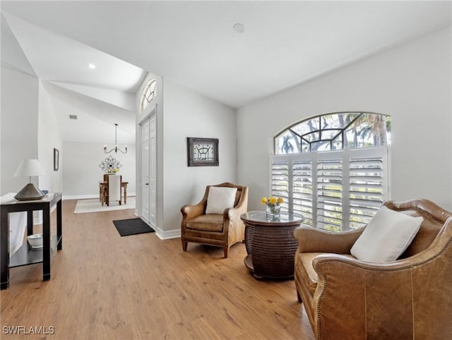 living area with light wood-type flooring, lofted ceiling, and baseboards