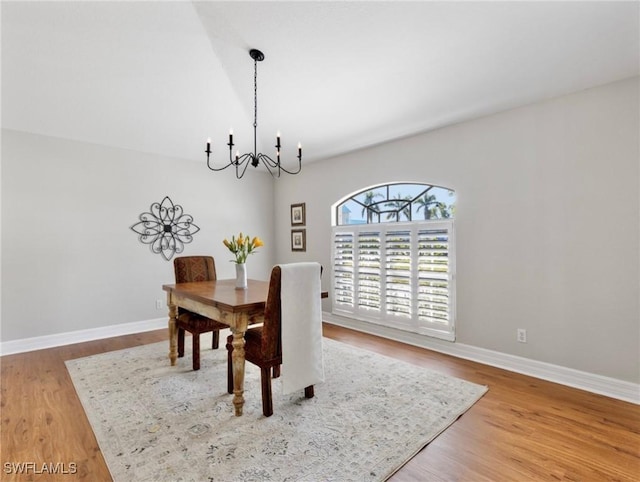 dining space featuring baseboards, an inviting chandelier, and wood finished floors