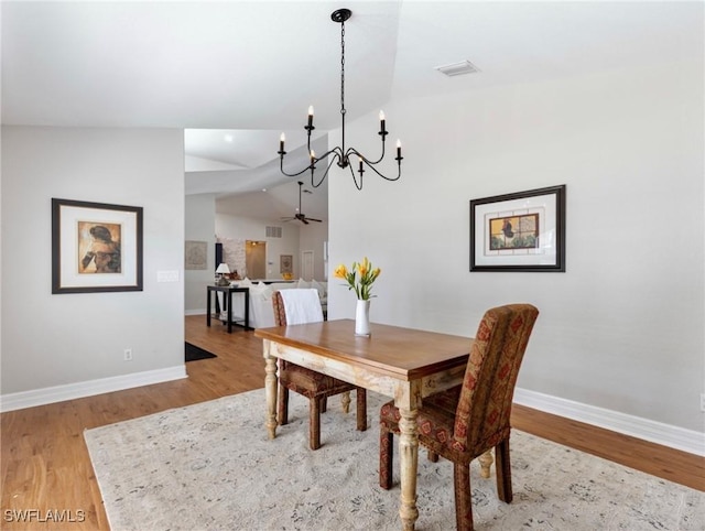 dining space featuring light wood finished floors, baseboards, and vaulted ceiling