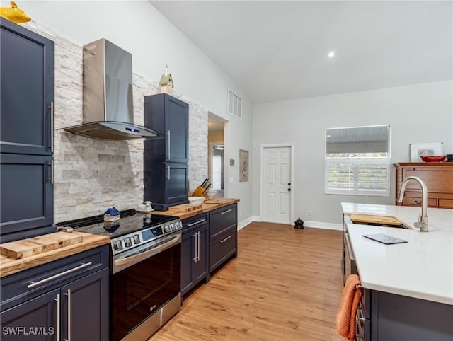 kitchen with visible vents, decorative backsplash, stainless steel electric range oven, wall chimney range hood, and wooden counters