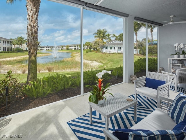 sunroom featuring a water view and ceiling fan