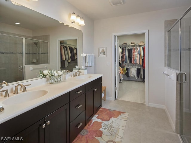 full bath featuring double vanity, a shower stall, tile patterned floors, and a sink