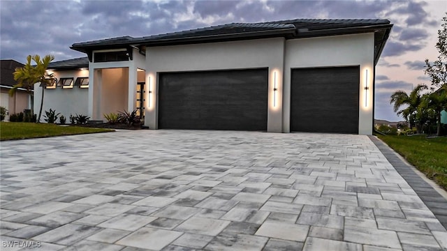 view of front of house featuring a garage, decorative driveway, and stucco siding