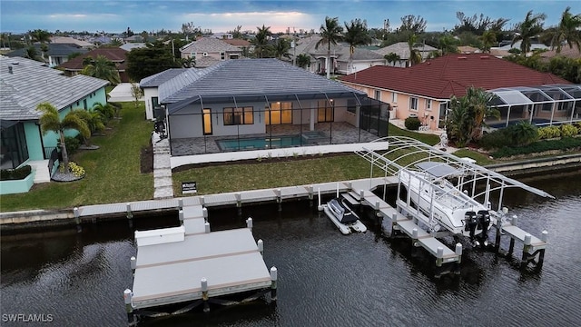 rear view of property featuring boat lift, a water view, a lawn, a lanai, and an outdoor pool