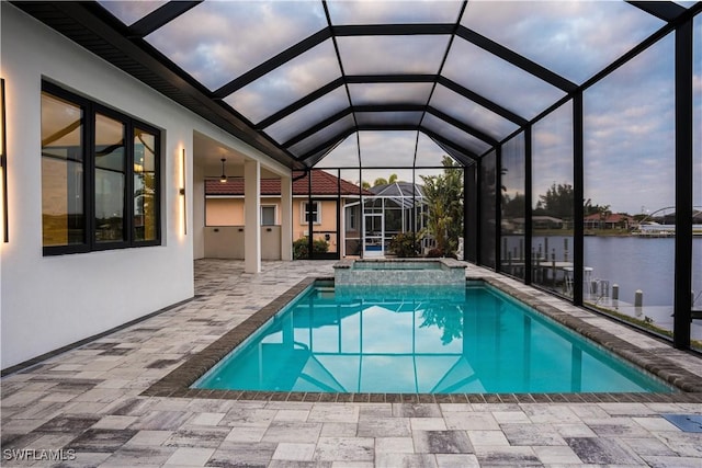 view of swimming pool featuring a patio, a pool with connected hot tub, a water view, a ceiling fan, and a lanai