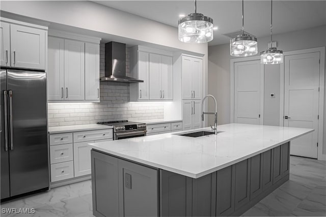 kitchen with stainless steel appliances, a sink, marble finish floor, wall chimney range hood, and an island with sink