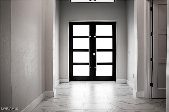 entrance foyer featuring marble finish floor, french doors, and baseboards