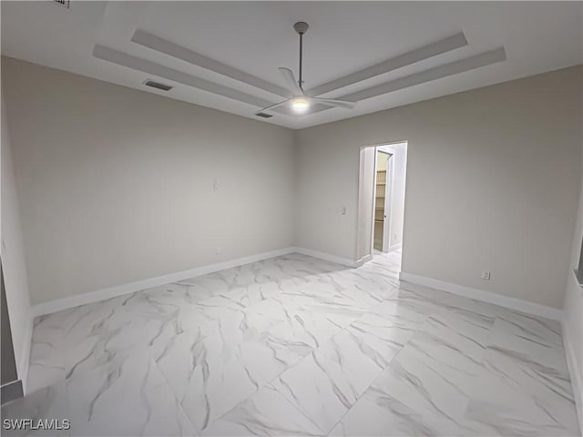 spare room featuring marble finish floor, a raised ceiling, visible vents, and baseboards