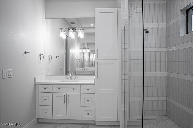 full bath with marble finish floor, tiled shower, vanity, and baseboards