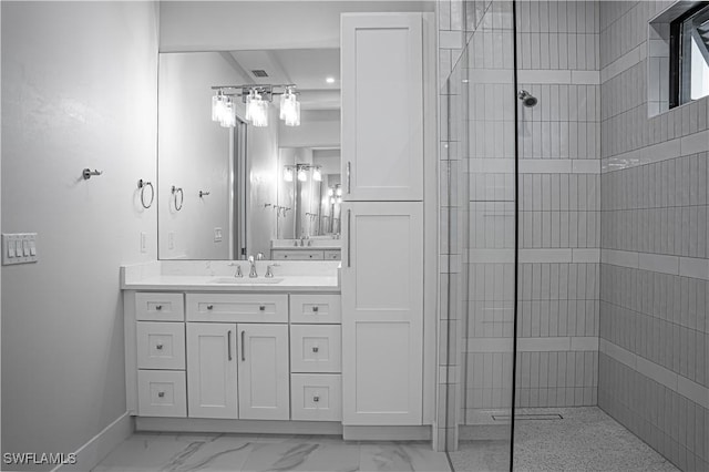 full bath featuring marble finish floor, tiled shower, vanity, and baseboards