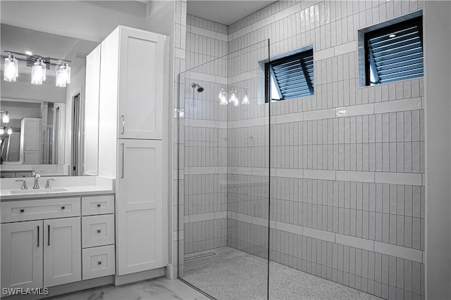 full bathroom with marble finish floor, vanity, and a walk in shower