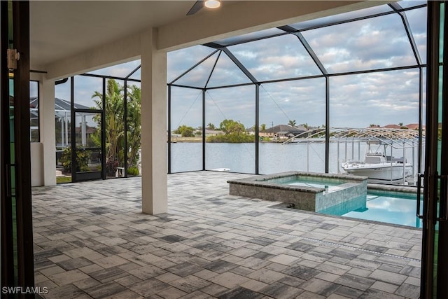 view of patio / terrace with a water view, glass enclosure, and a pool with connected hot tub