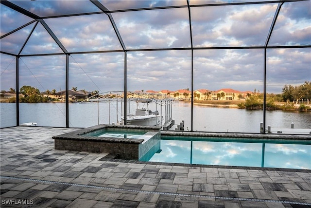 view of swimming pool featuring a pool with connected hot tub, a lanai, a water view, and a patio