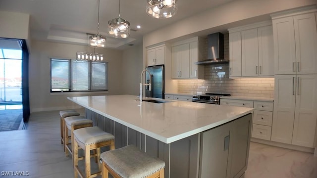 kitchen featuring a center island with sink, decorative backsplash, appliances with stainless steel finishes, a sink, and wall chimney exhaust hood