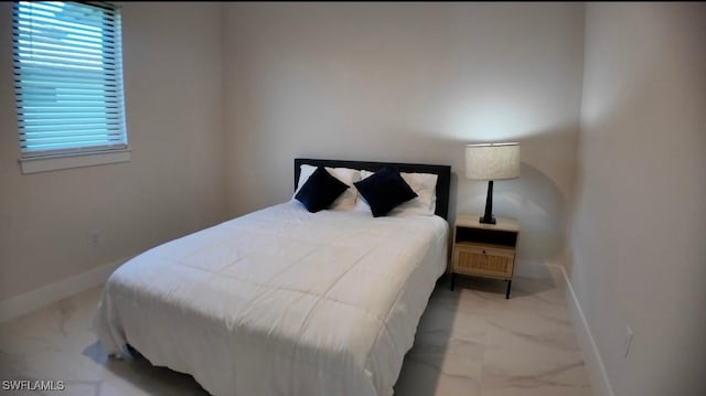 bedroom featuring marble finish floor and baseboards