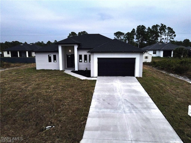 view of front of property featuring driveway, an attached garage, a front lawn, and stucco siding