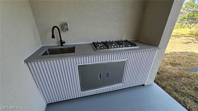 interior details featuring stainless steel gas cooktop, a sink, and a textured wall